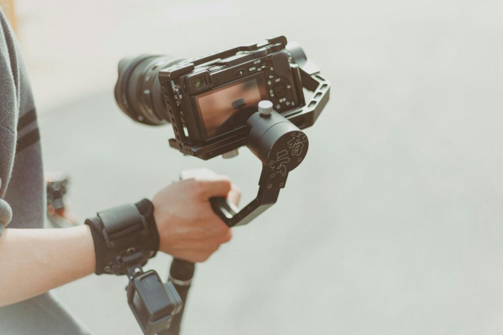 Close-up of a videographer holding a modern camera with stabilizer outdoors. Capturing high-quality footage.